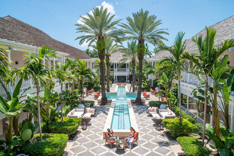 Courtyard pool lined with palm trees and lounge seating