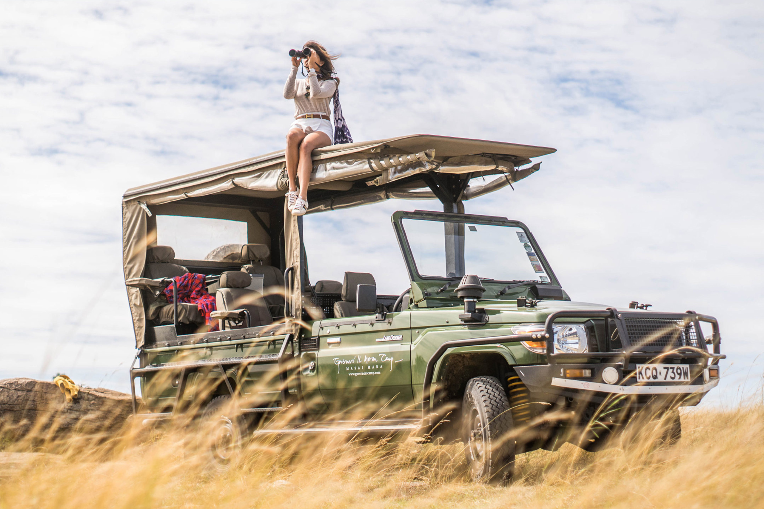 Safari vehicle parked in tall grass on the savanna