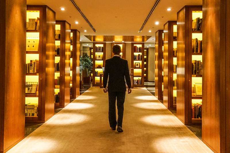 Person walking through a wood-paneled library corridor