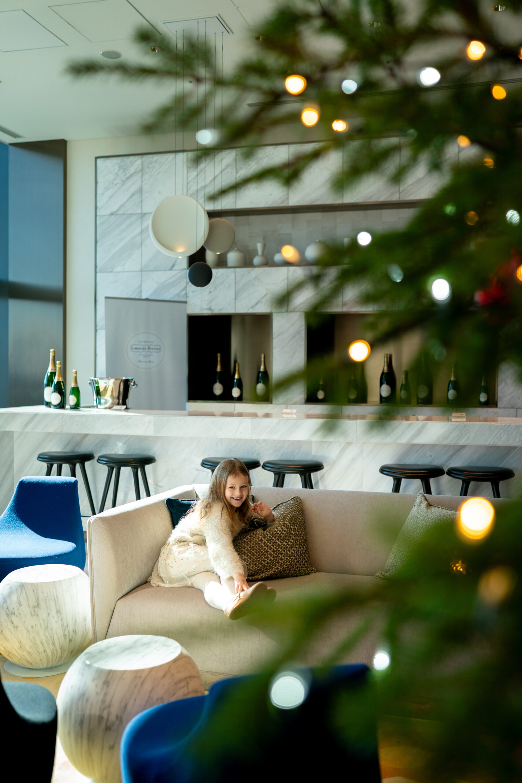 Guest reclining on a lounge sofa reaching for a cocktail on a low round table