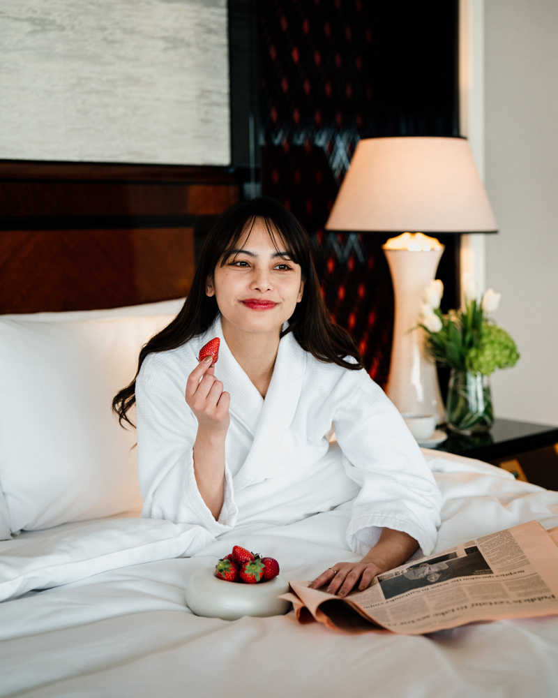 Guest reclining on a lounge sofa reaching for a cocktail on a low round table