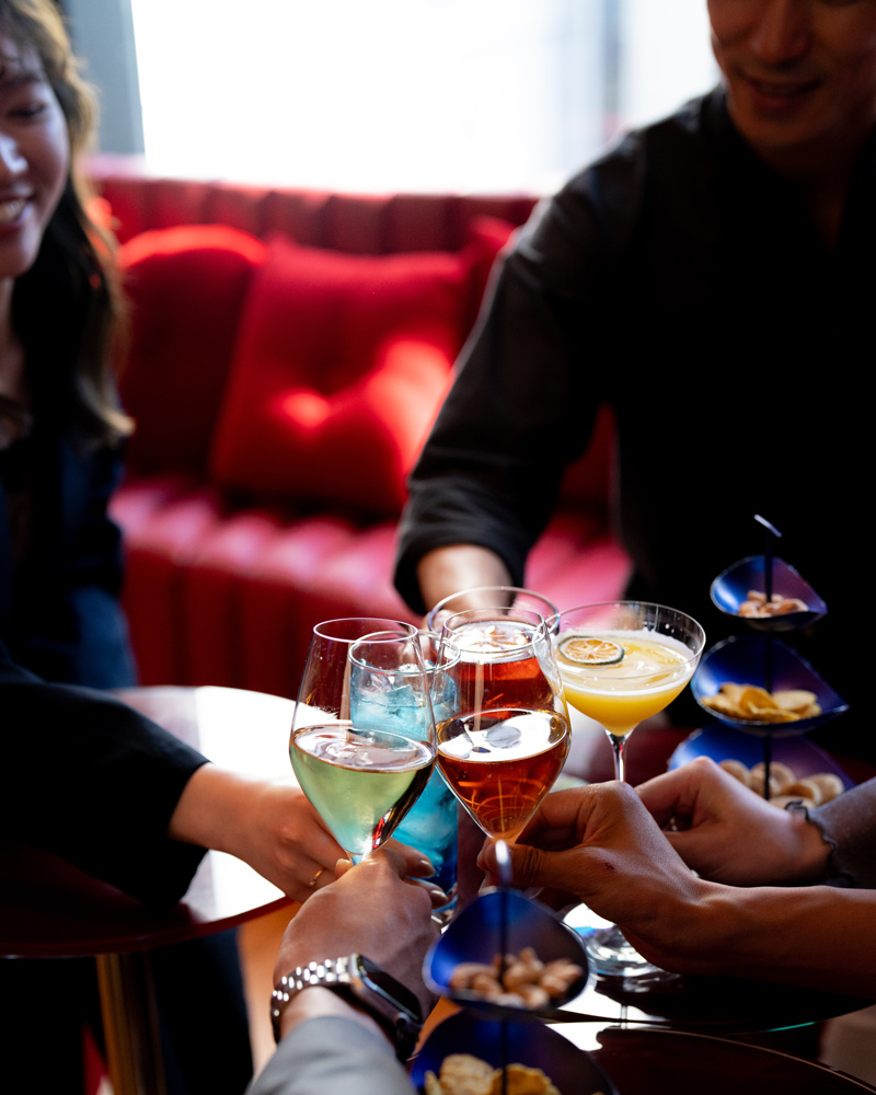 Guest reclining on a lounge sofa reaching for a cocktail on a low round table